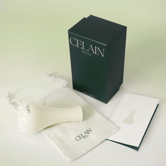 Gua Sha en forme de pot de fleur en céramique avec base à picots texturés pour le massage stimulant et le drainage lymphatique. Avec son étui en tissu et sa boîte.