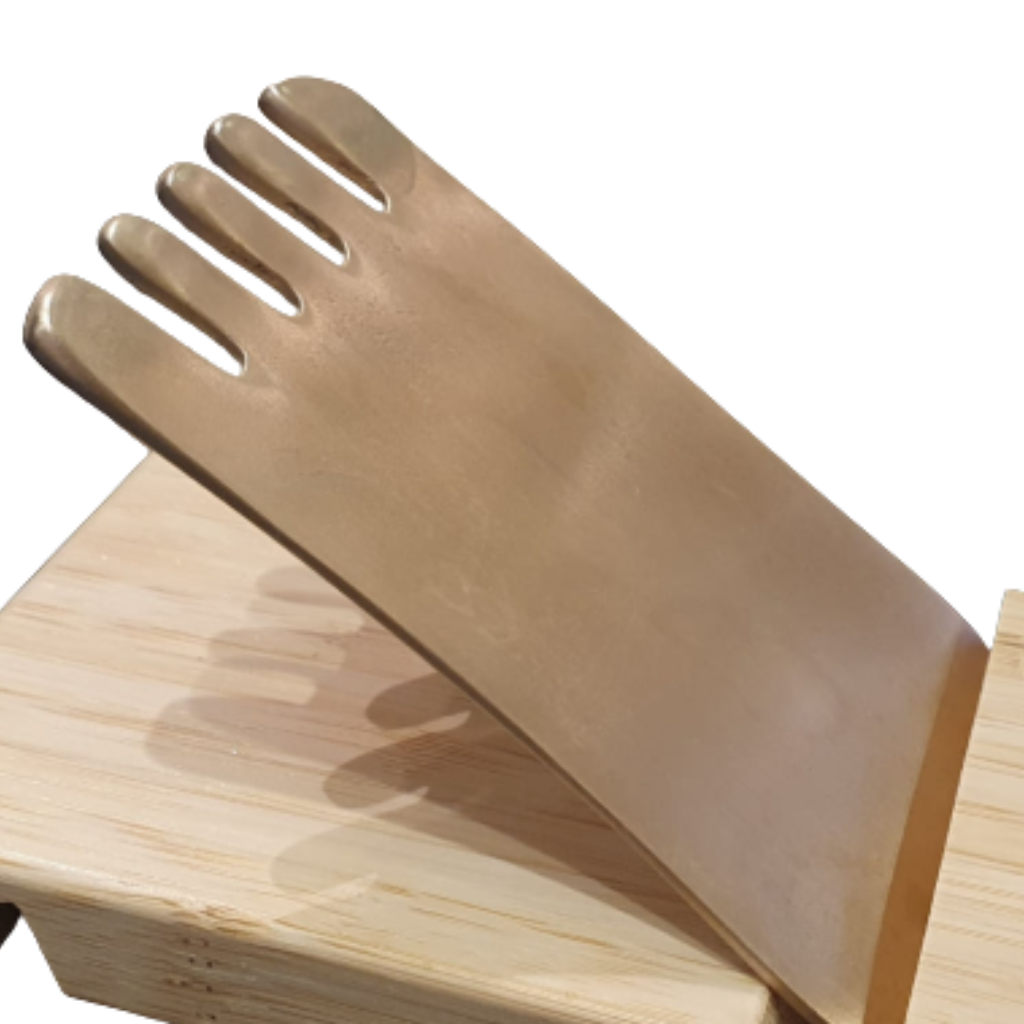 Outil de massage Gua Sha en laiton en forme de peigne à dents larges, présenté de face sur son support de rangement en bois clair poli.