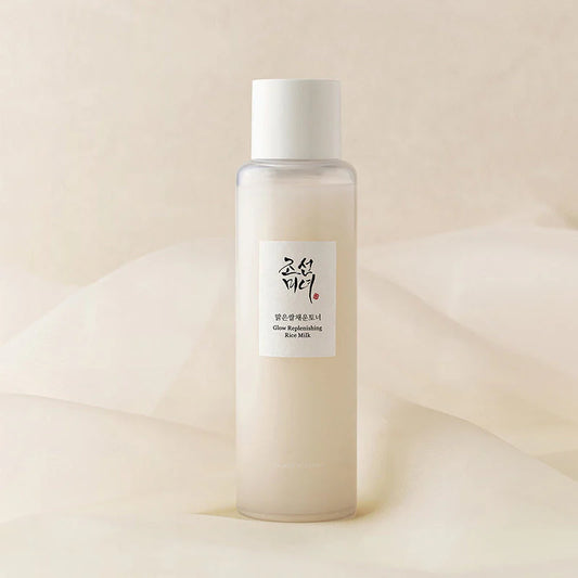 Flacon en plastique transparent du tonique BEAUTY OF JOSEON Glow Refreshing Rice Milk sur fond voile de soie crème.