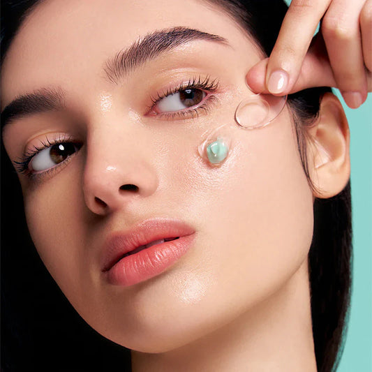 Mannequin appliquant sur son visage à l’aide d’une spatule une capsule de la crème : VT COSMETICS PDRN CAPSULE CREAM