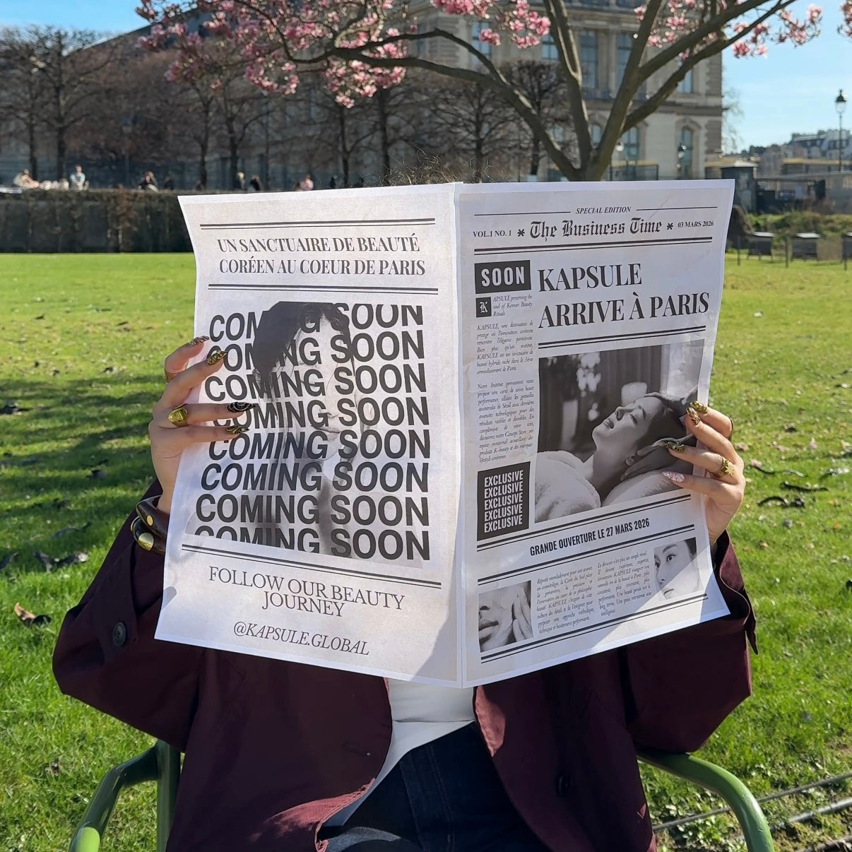 Photo d’une femme tenant un journal devant son visage. Le journal annonce l’arrivée de Kapsule à paris