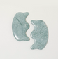 Paire d'outils de massage facial Gua Sha de forme ergonomique « couronne », en pierre de jade côte à côte pour un soin du visage décongestionnant et sculptant.