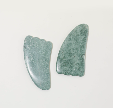 Paire d'outils de massage facial Gua Sha de forme ergonomique triangle, en pierre de jade côte à côte pour un soin du visage décongestionnant et sculptant. 