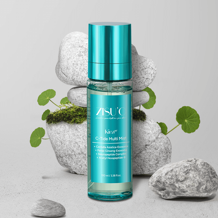 Brume Kira C-Tide Multi Mist de ZISU’C. Flacon transparent avec une étiquette bleu et capuchon bleu sur fond gris avec des galets et des plantes de cica.
